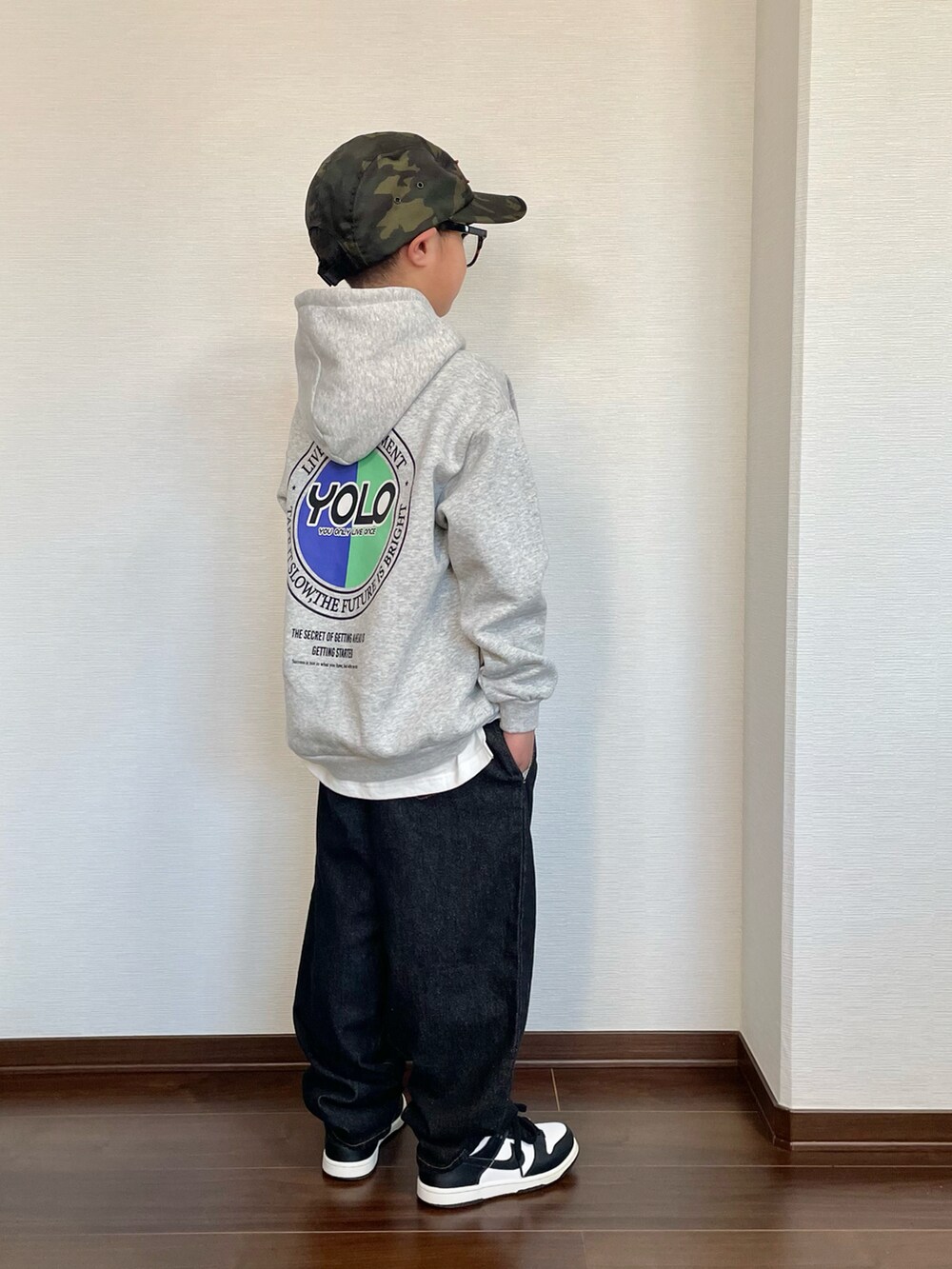 グレー系のパーカー、ブラック系のデニムパンツ、ホワイト系のスニーカーを着用したキッズの冬コーディネートの2枚目の写真