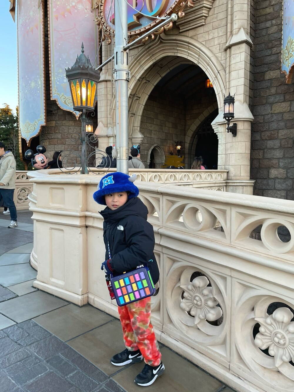 オレンジ系のスウェットパンツ、ブラック系のスニーカー、ブラック系のダウンジャケット/コートを着用したキッズの冬コーディネートの3枚目の写真