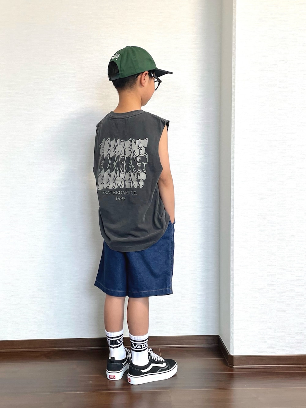 ブラック系のタンクトップ、ブラック系のスニーカー、ブルー系のデニムパンツを着用したキッズの夏コーディネートの2枚目の写真