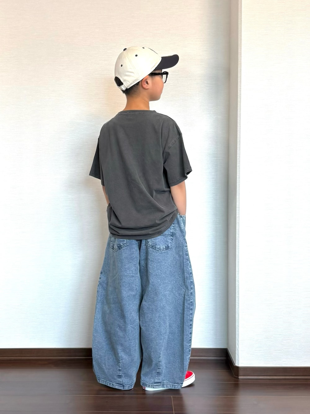 ブラック系のTシャツ/カットソー、ブルー系のデニムパンツ、レッド系のスニーカーを着用したキッズの春コーディネートの3枚目の写真