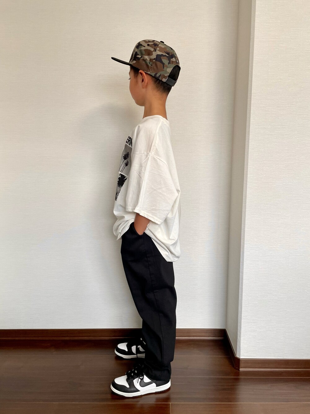 ブラック系のスニーカー、ホワイト系のTシャツ/カットソー、ブラック系のカーゴパンツを着用したキッズの夏コーディネートの2枚目の写真