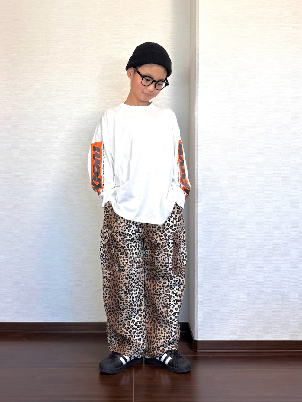 ブラック系のスニーカー、ホワイト系のTシャツ/カットソー、ブラウン系のカーゴパンツを着用したキッズの秋コーディネートの2枚目の写真