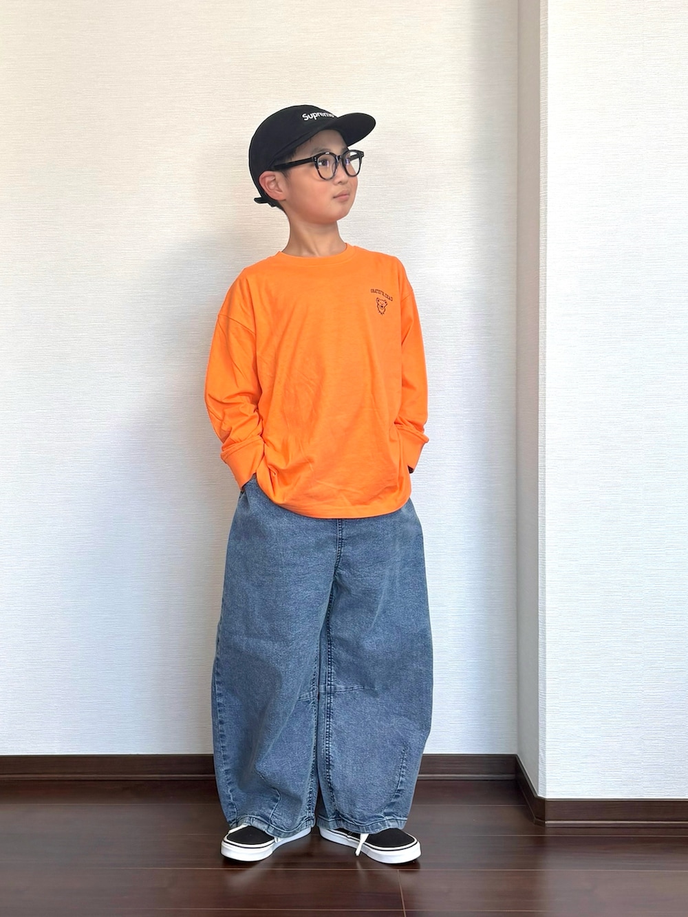 オレンジ系のTシャツ/カットソー、ブラック系のスニーカー、ブルー系のデニムパンツを着用したキッズの春コーディネートの2枚目の写真