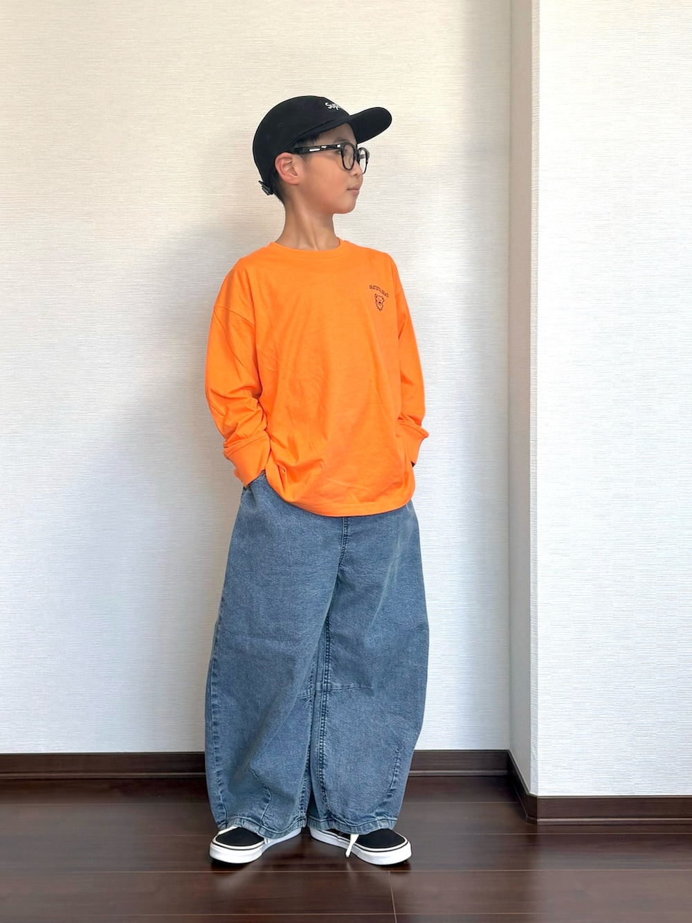オレンジ系のTシャツ/カットソー、ブラック系のスニーカー、ブルー系のデニムパンツを着用したキッズの春コーディネートの3枚目の写真