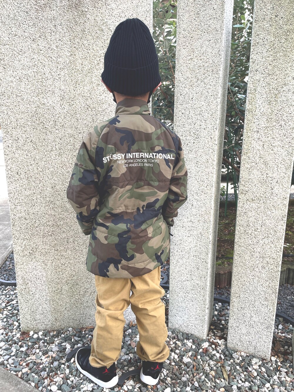 グリーン系のブルゾン、ベージュ系のチノパンツ、ブラック系のスニーカーを着用したキッズの秋コーディネートの2枚目の写真