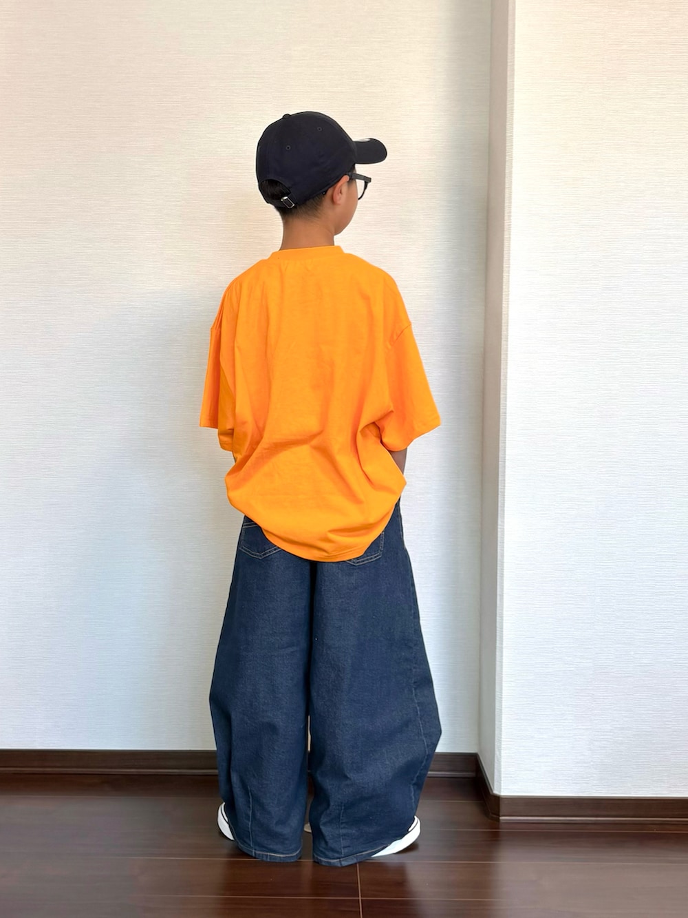 オレンジ系のTシャツ/カットソー、ブルー系のデニムパンツ、ブラック系のスニーカーを着用したキッズの夏コーディネートの4枚目の写真