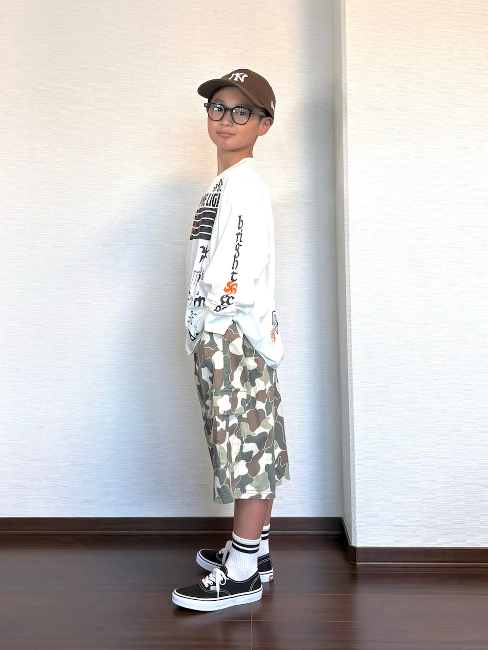 ホワイト系のTシャツ/カットソー、ベージュ系のカーゴパンツ、ブラック系のスニーカーを着用したキッズの秋コーディネートの3枚目の写真