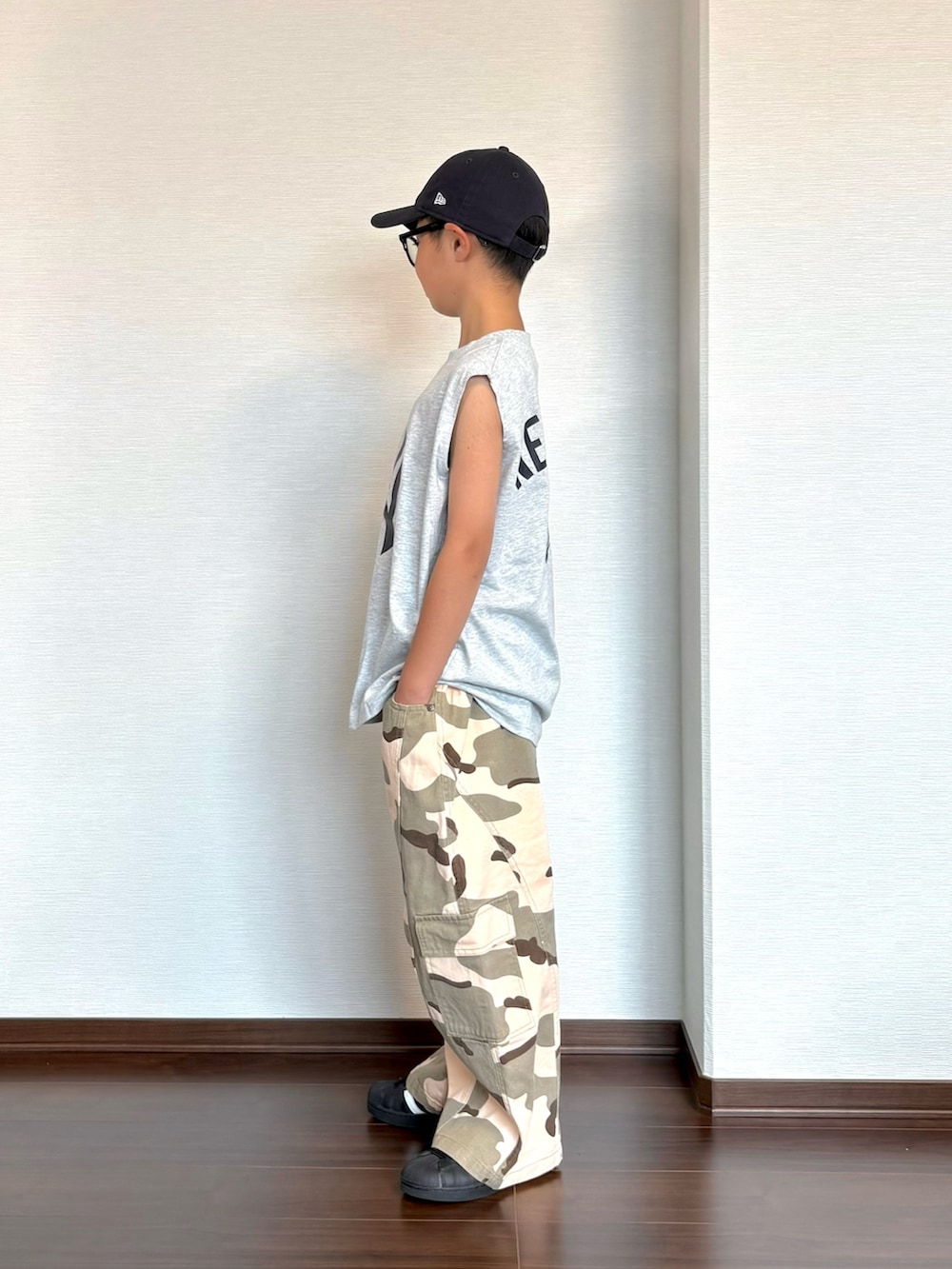 グリーン系のカーゴパンツ、ブラック系のスニーカー、グレー系のタンクトップを着用したキッズの夏コーディネートの3枚目の写真