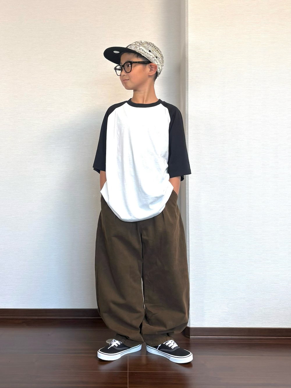 ホワイト系のTシャツ/カットソー、ブラウン系のその他パンツ、ブラック系のスニーカーを着用したキッズの秋コーディネートの2枚目の写真