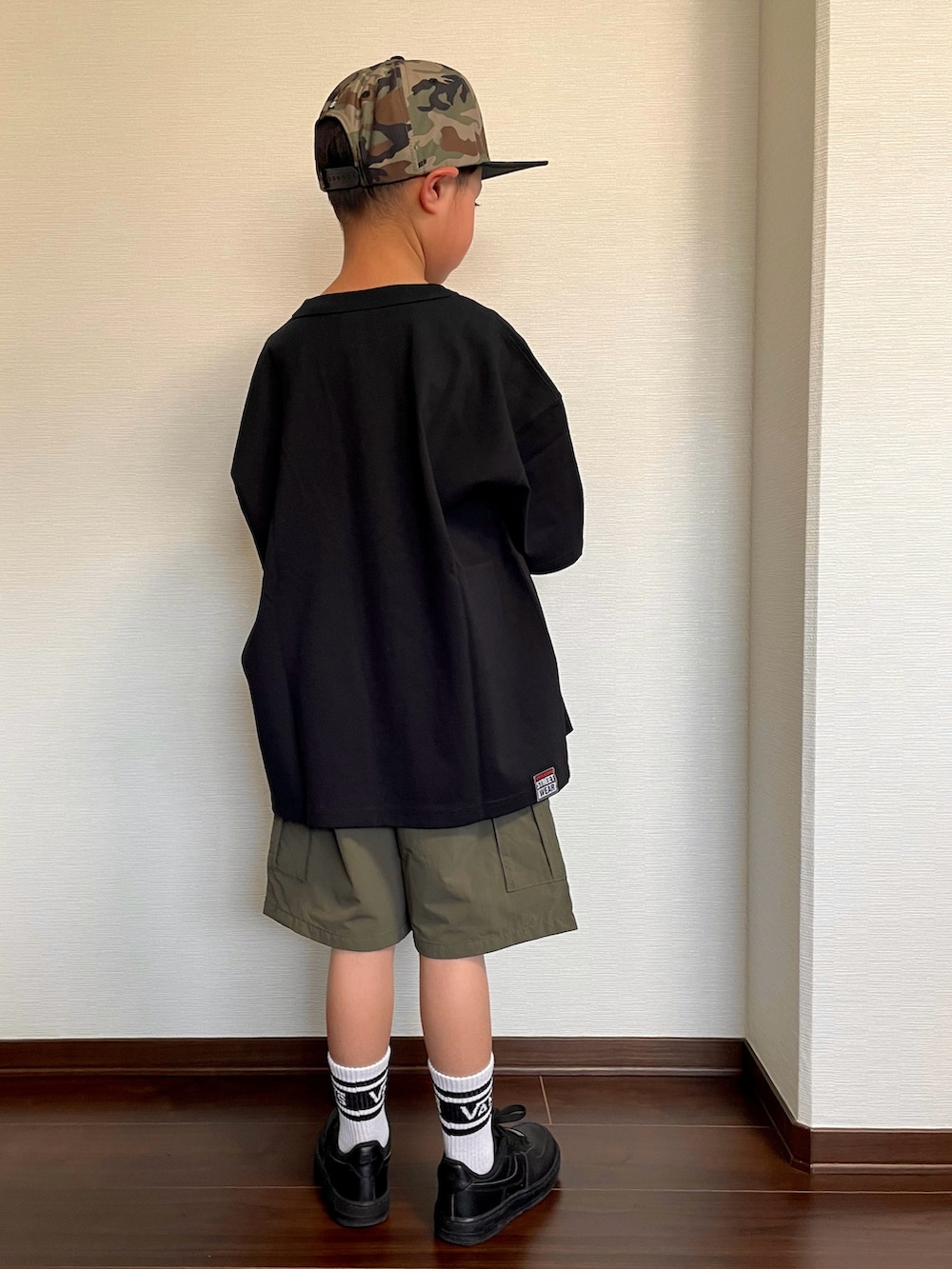 ブラック系のTシャツ/カットソー、グリーン系のカーゴパンツ、ブラック系のスニーカーを着用したキッズの春コーディネートの2枚目の写真