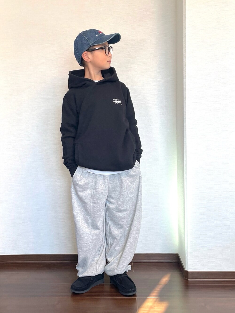 グレー系のスウェットパンツ、ブラック系のパーカー、ブラック系のシューズを着用したキッズの冬コーディネートの2枚目の写真