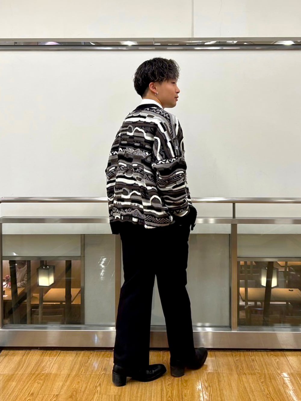 ブラック系のスラックス、ブラック系のブーツ、ブラック系のカーディガン/ボレロを着用したメンズの秋コーディネートの2枚目の写真