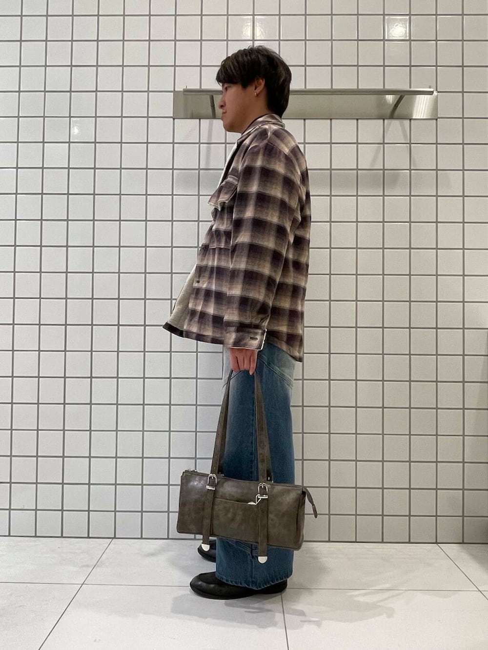 ブラック系のニット/セーター、ブルー系のその他パンツ、ブラウン系のボストンバッグを着用したメンズの冬コーディネートの2枚目の写真