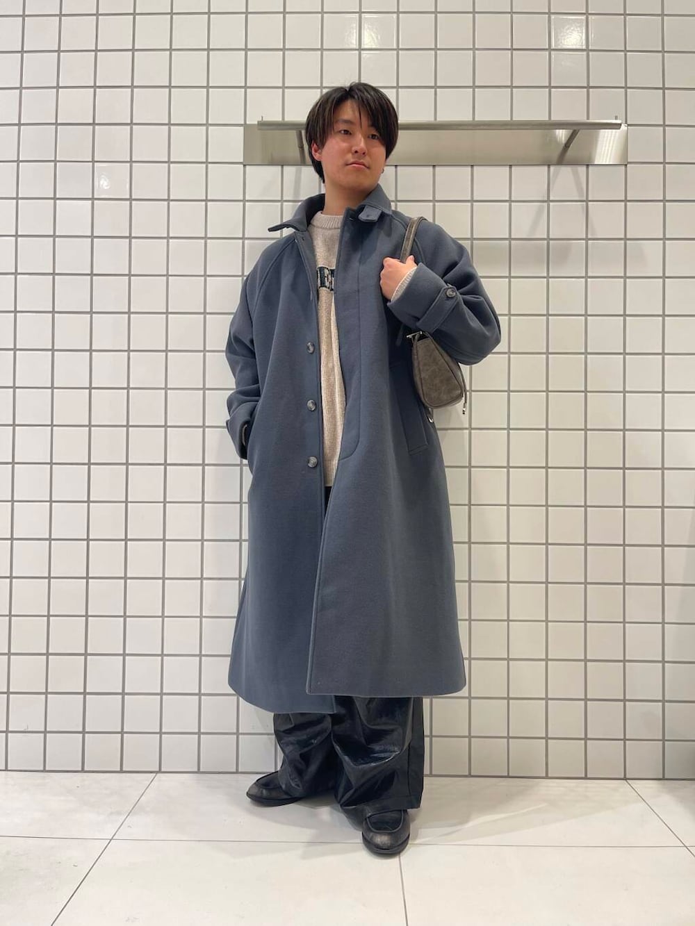 ブルー系のステンカラーコート、ブラウン系のボストンバッグ、ブラック系のその他パンツを着用したメンズの冬コーディネートの2枚目の写真
