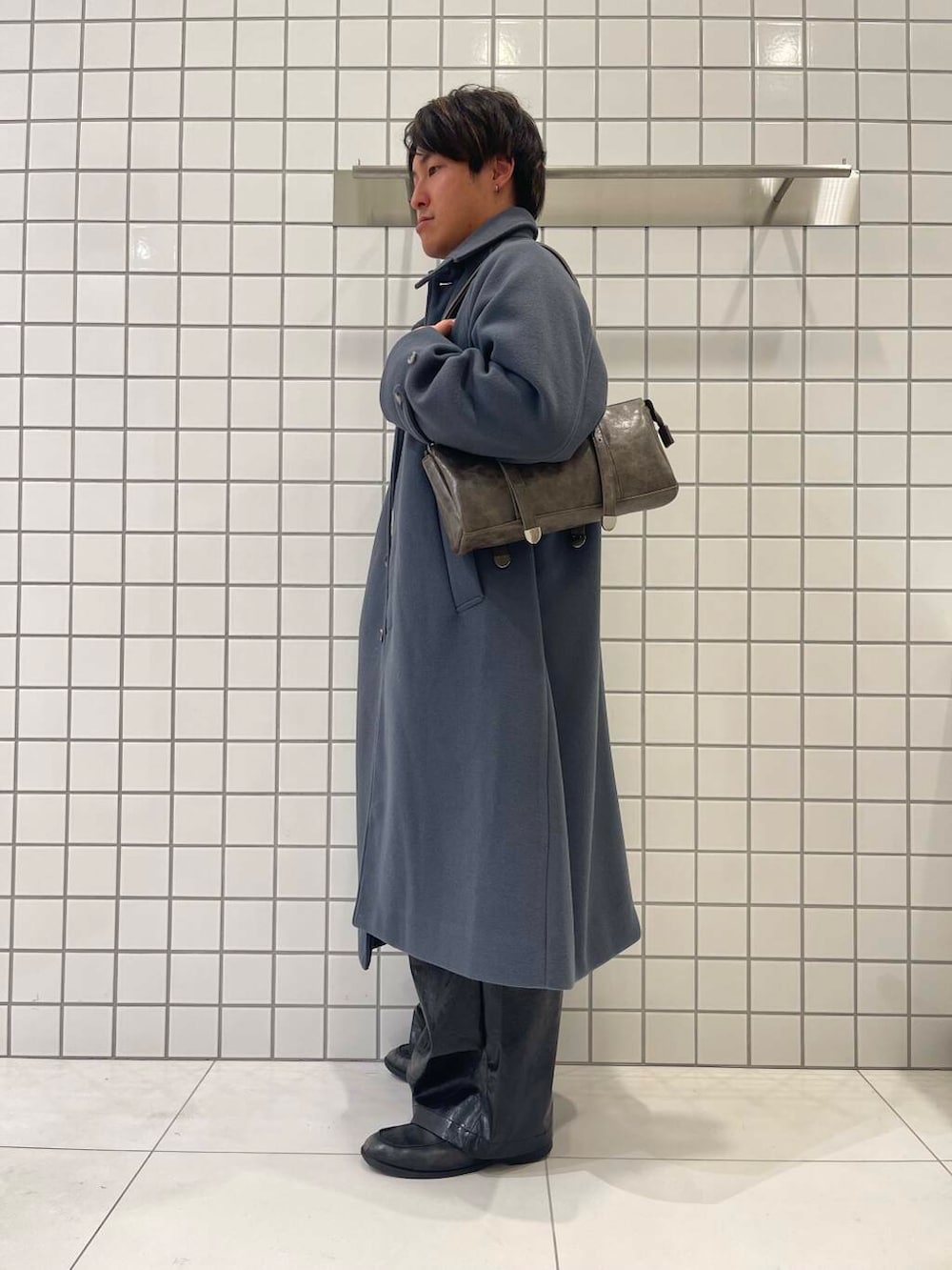 ブルー系のステンカラーコート、ブラウン系のボストンバッグ、ブラック系のその他パンツを着用したメンズの冬コーディネートの3枚目の写真