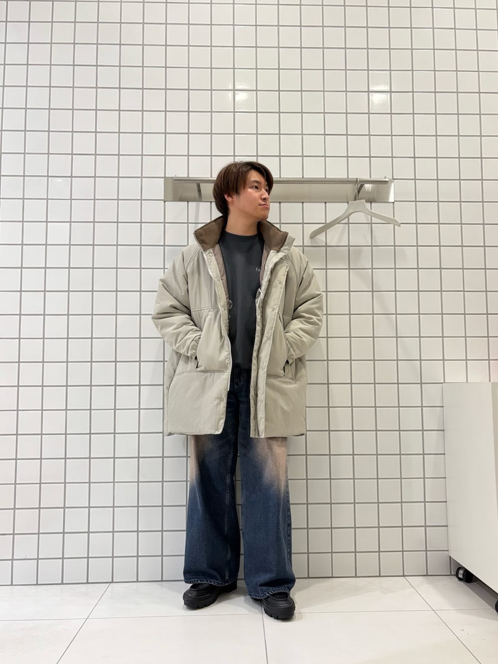 グレー系のスウェット、ブルー系のデニムパンツ、ベージュ系のダウンジャケット/コートを着用したメンズの秋コーディネートの4枚目の写真