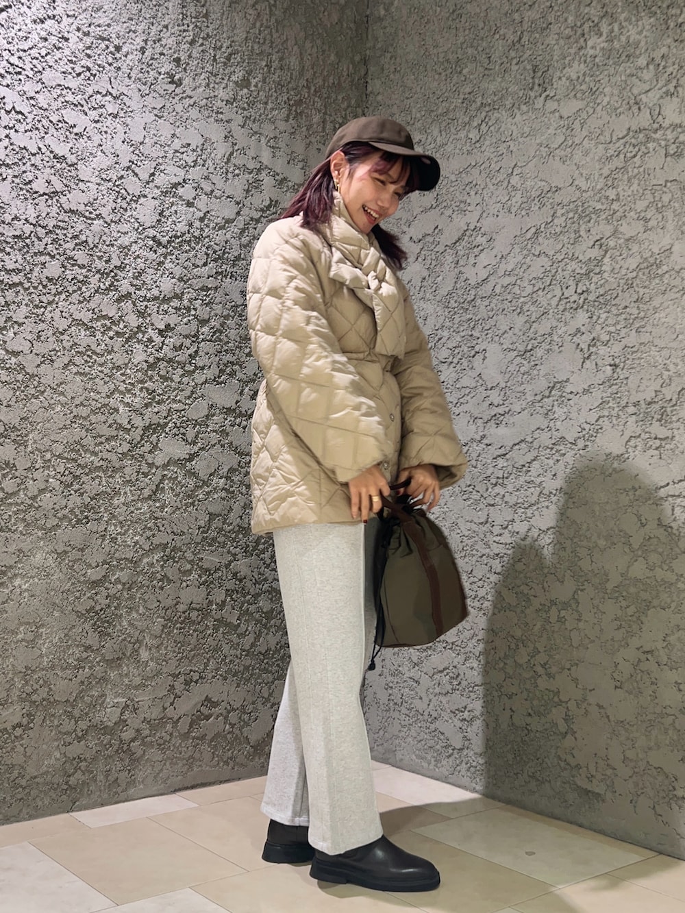 ベージュ系のダウンジャケット/コート、ブラウン系のトートバッグ、グレー系のスウェットパンツを着用したレディースの冬コーディネートの2枚目の写真
