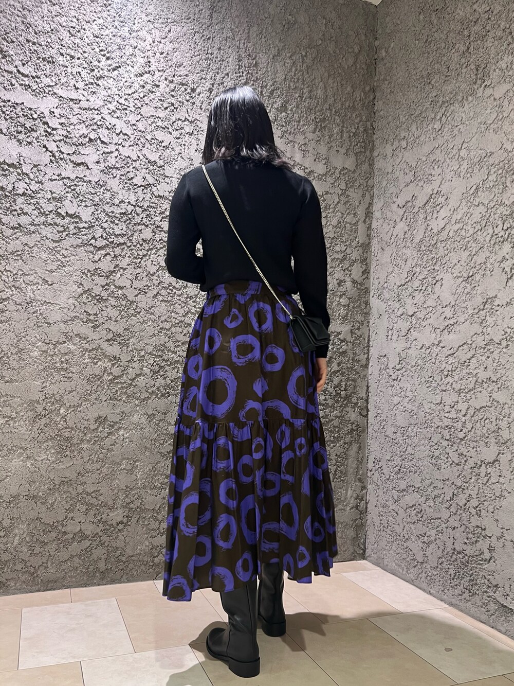 ブラック系のカーディガン/ボレロ、ブラウン系のスカート、ブラック系のブーツを着用したレディースの秋コーディネートの3枚目の写真