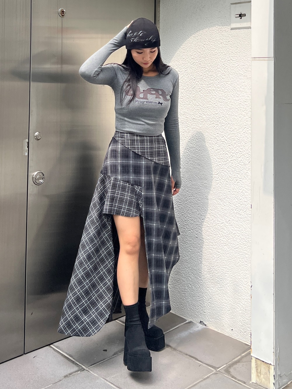 グレー系のTシャツ/カットソー、ブラック系のスカート、ブラック系のブーツを着用したレディースの秋コーディネートの3枚目の写真