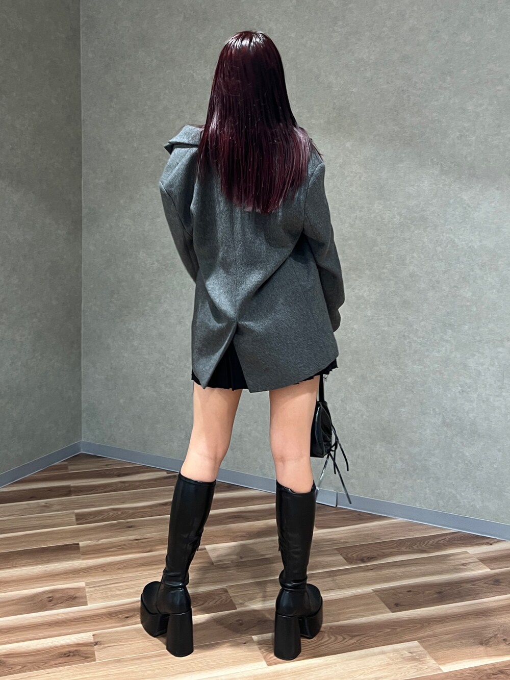 ブラック系のニット/セーター、グレー系のテーラードジャケット、ブラック系のスカートを着用したレディースの秋コーディネートの4枚目の写真