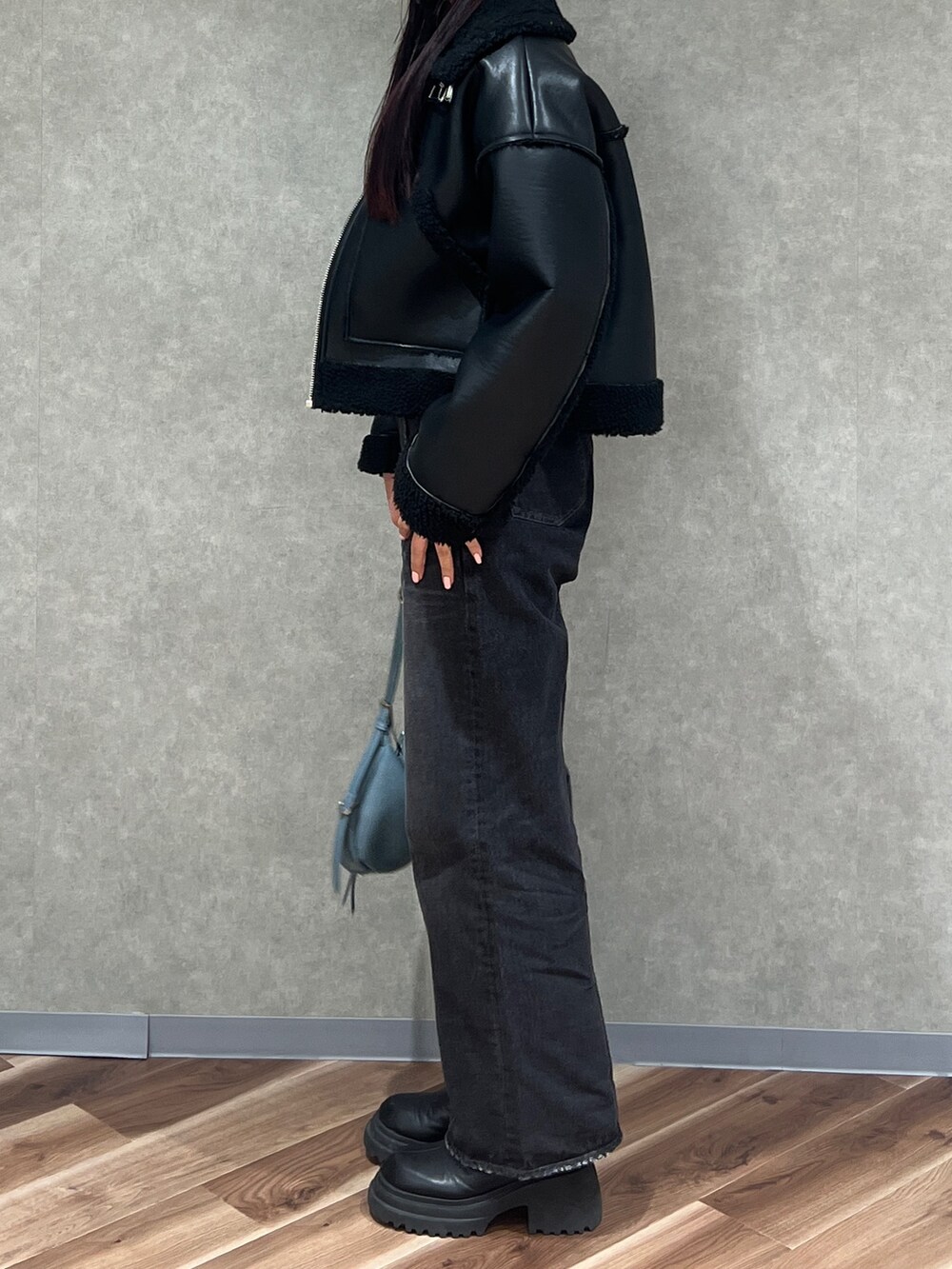 ブラック系のブルゾン、ブルー系のニット/セーター、ブラック系のデニムパンツを着用したレディースの冬コーディネートの2枚目の写真