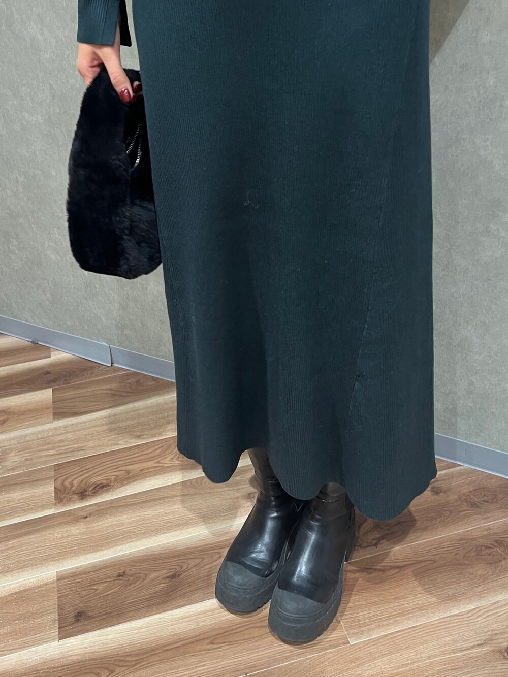 グリーン系のワンピース、ホワイト系のチェスターコート、ブラック系のハンドバッグを着用したレディースの冬コーディネートの5枚目の写真