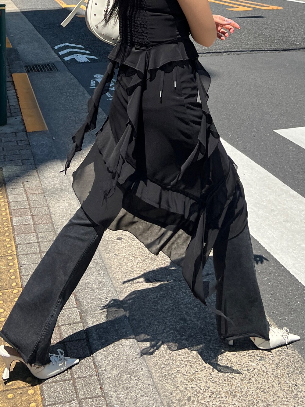 ブラック系のTシャツ/カットソー、ブラック系のスカート、ブラック系のデニムパンツを着用したレディースの春コーディネートの5枚目の写真