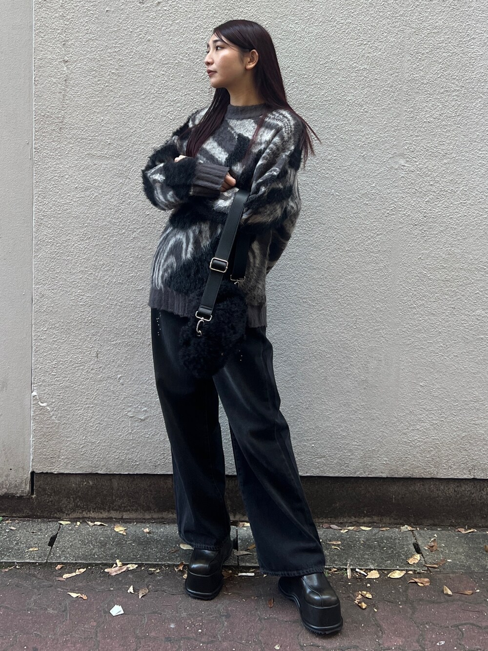 ブラック系のデニムパンツ、グレー系のニット/セーター、ブラック系のハンドバッグを着用したレディースの冬コーディネートの2枚目の写真