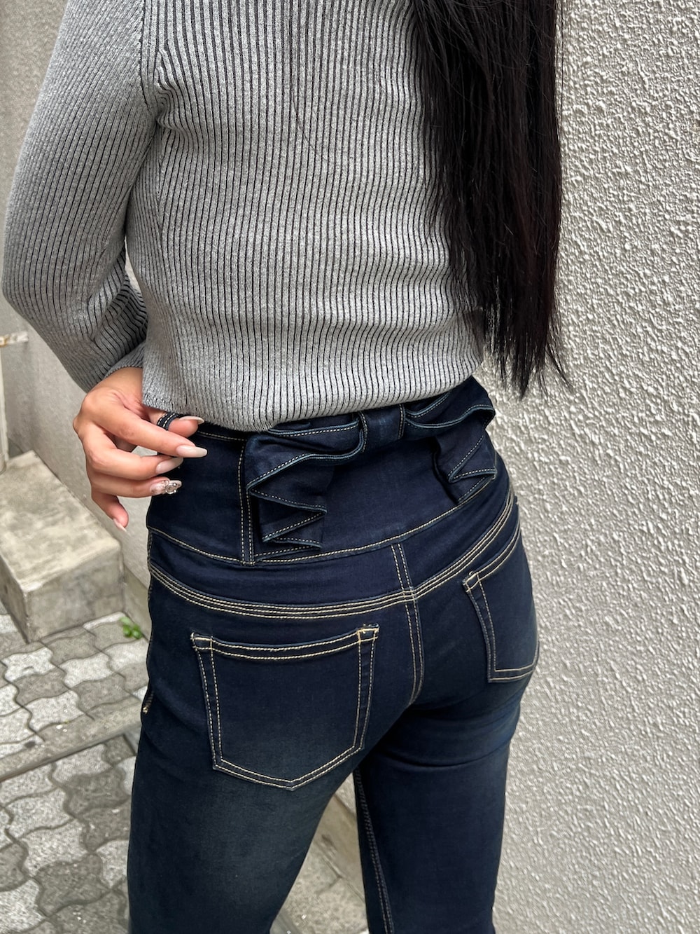 グレー系のニット/セーター、ブルー系のデニムパンツ、ブラック系のブーツを着用したレディースの秋コーディネートの3枚目の写真