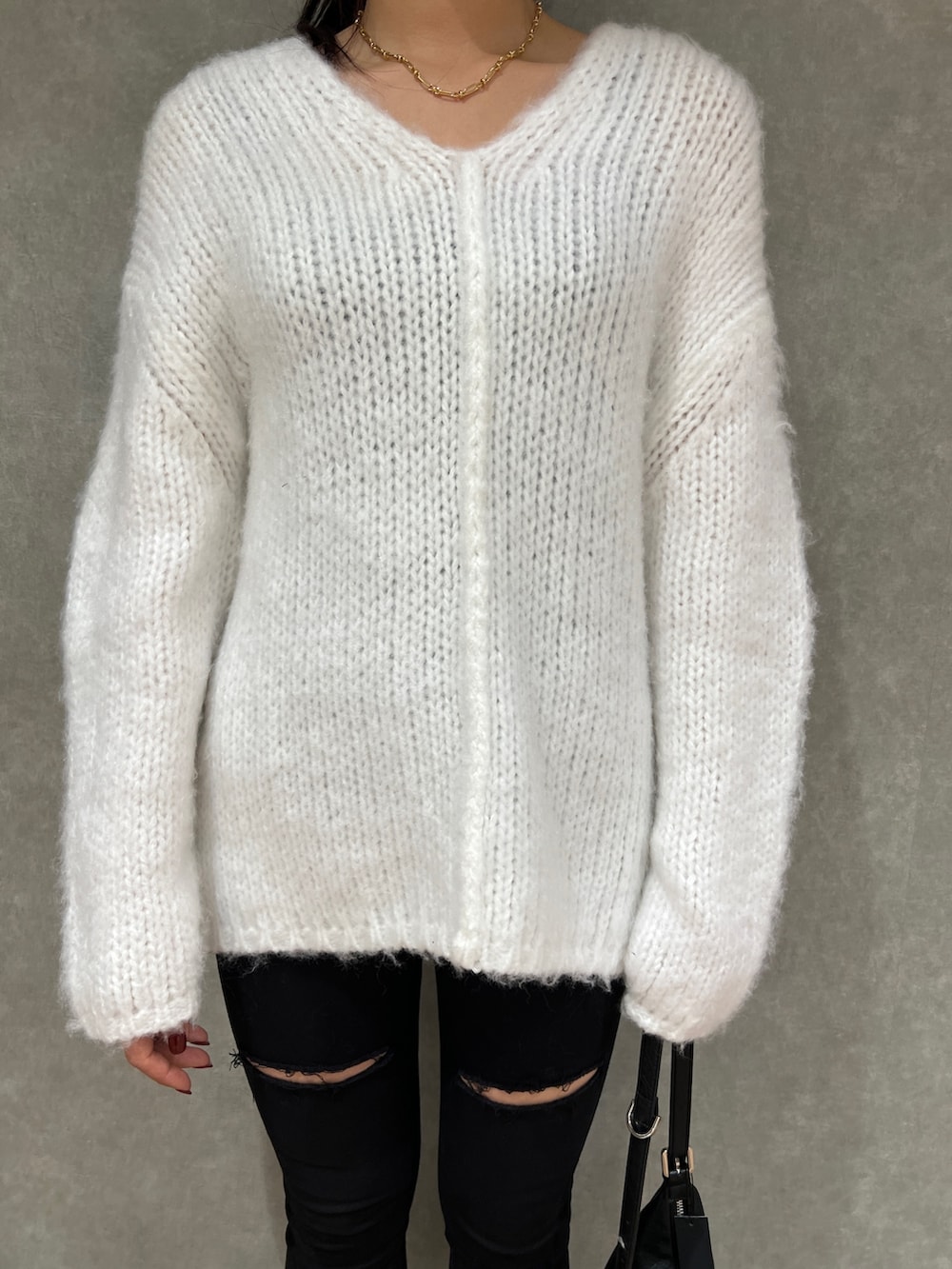 ホワイト系のニット/セーター、ブラック系のデニムパンツ、ブラック系のハンドバッグを着用したレディースの冬コーディネートの4枚目の写真