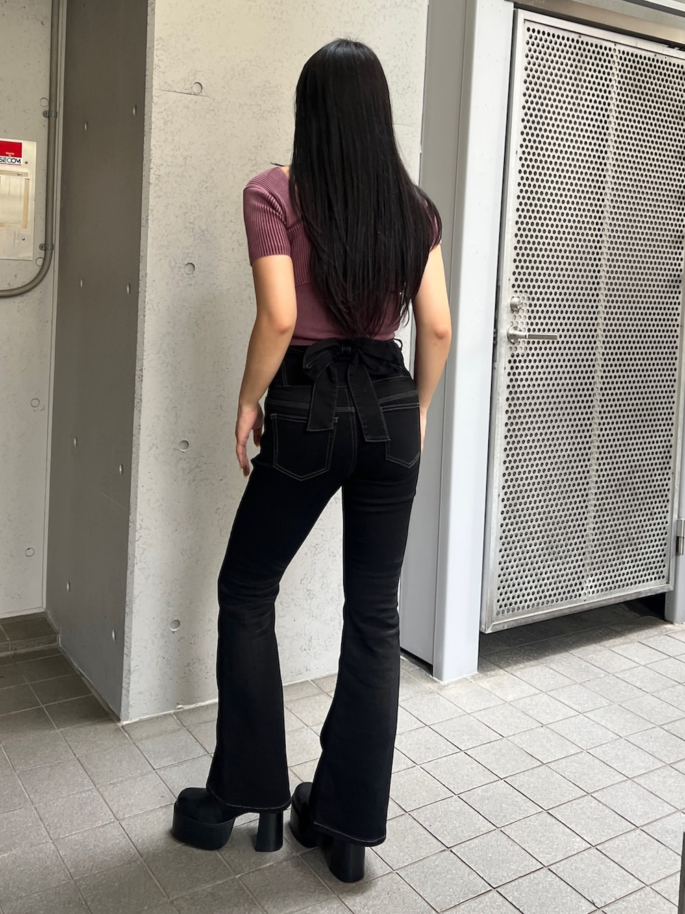 レッド系のニット/セーター、ブラック系のデニムパンツ、ブラック系のブーツを着用したレディースの夏コーディネートの3枚目の写真