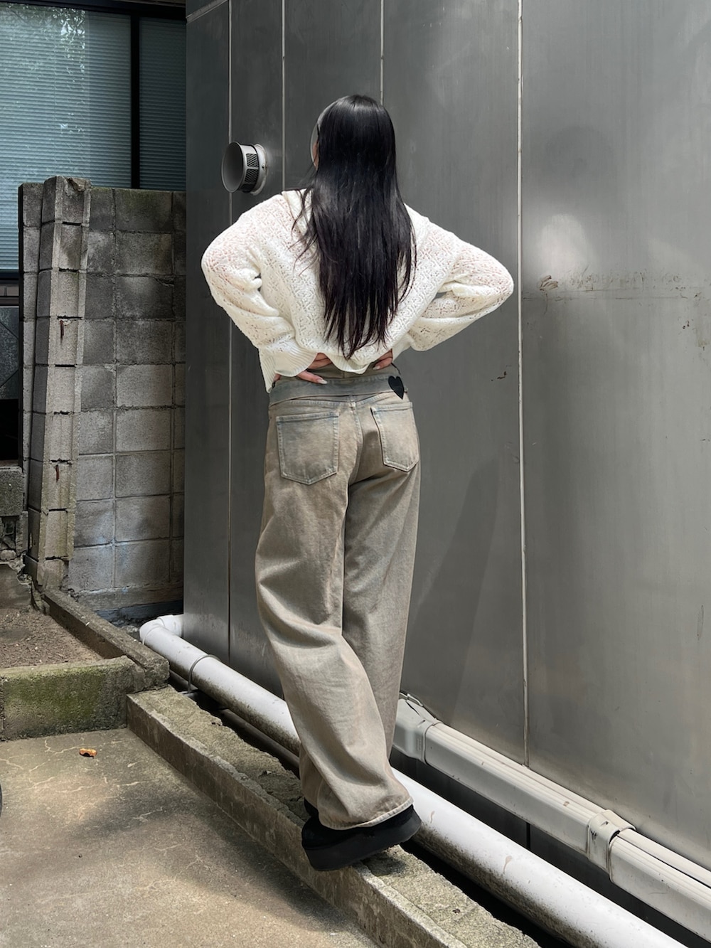 ホワイト系のニット/セーター、ホワイト系のキャミソール、ブラウン系のデニムパンツを着用したレディースの夏コーディネートの3枚目の写真