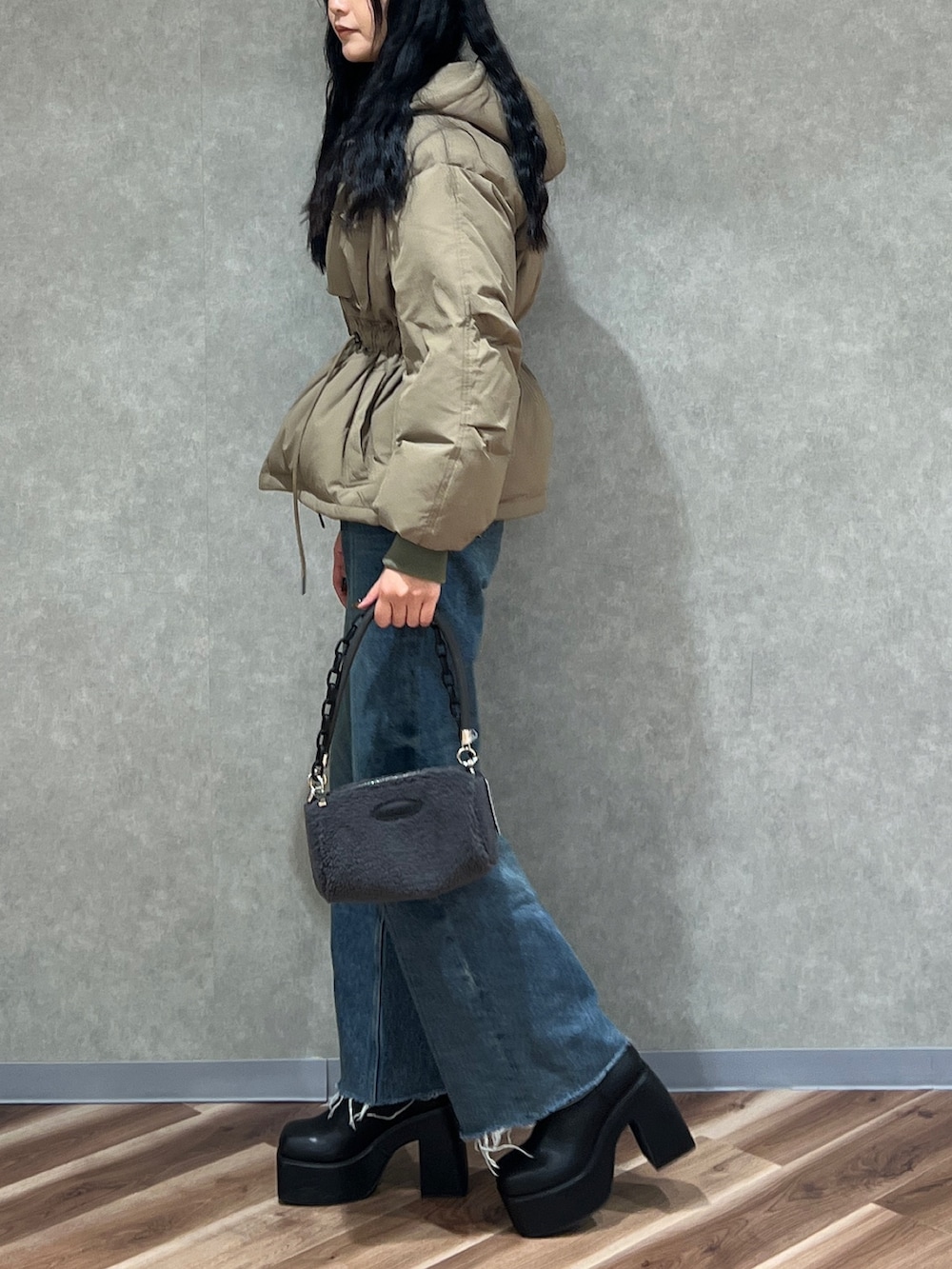 グリーン系のブルゾン、ブルー系のデニムパンツ、ブラック系のブーツを着用したレディースの秋コーディネートの2枚目の写真