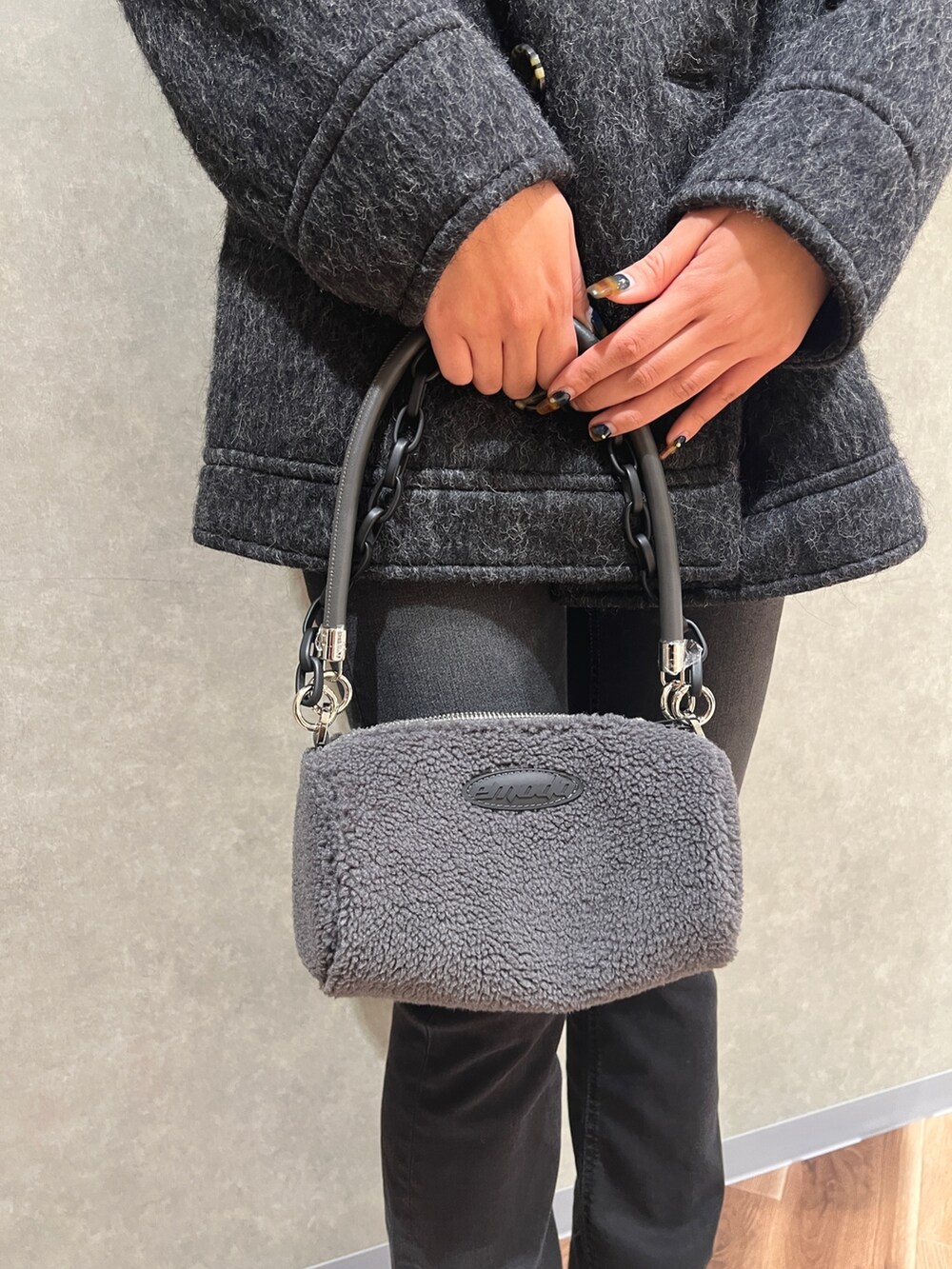 グレー系のピーコート、ブラック系のニット/セーター、ブラック系のデニムパンツを着用したレディースの秋コーディネートの6枚目の写真