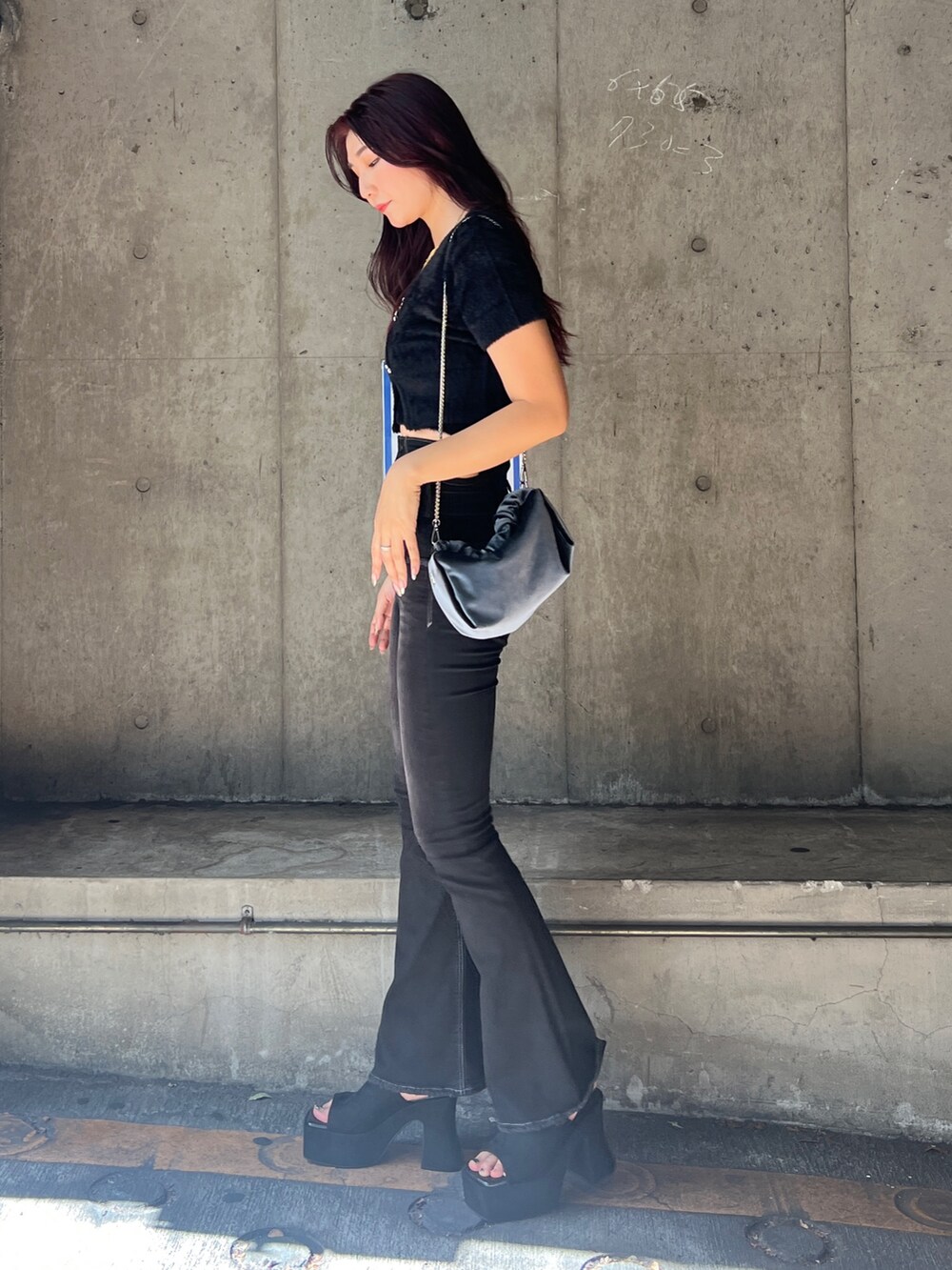 ブラック系のニット/セーター、ブラック系のデニムパンツ、グレー系のハンドバッグを着用したレディースの夏コーディネートの2枚目の写真