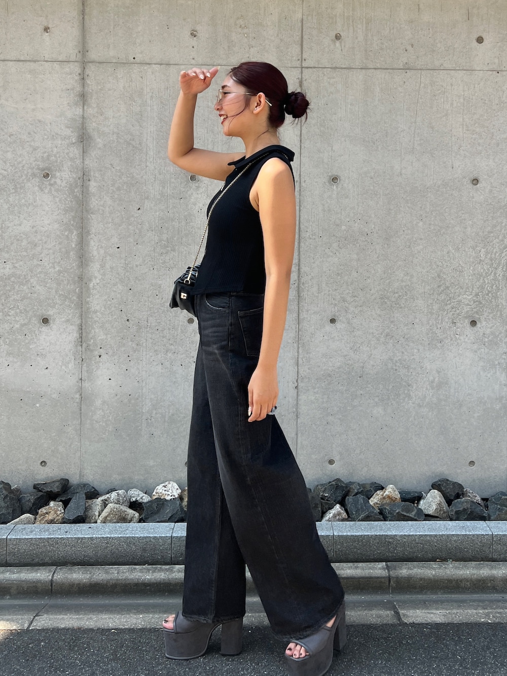 ブラック系のタンクトップ、ブラック系のデニムパンツ、グレー系のハンドバッグを着用したレディースの夏コーディネートの2枚目の写真
