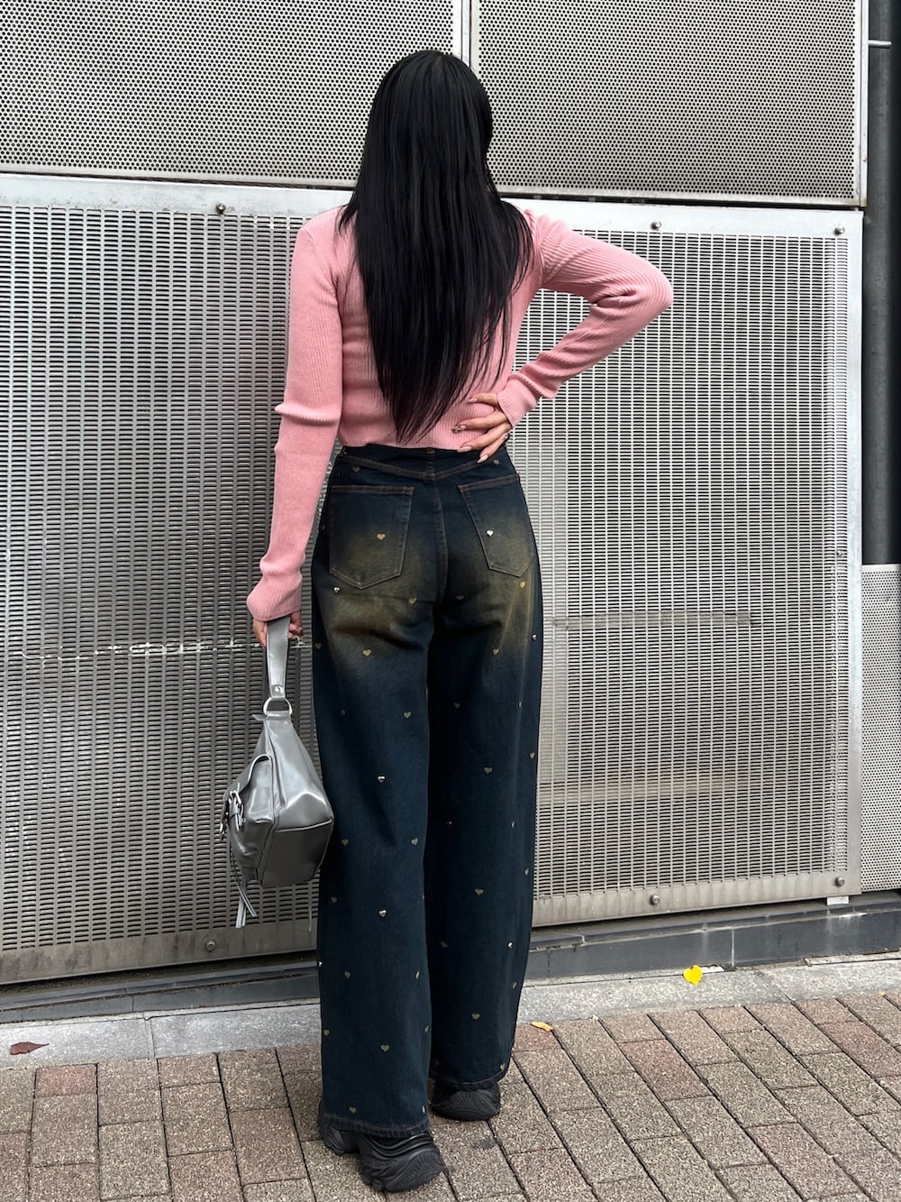 ピンク系のニット/セーター、ブルー系のデニムパンツ、ブラック系のスニーカーを着用したレディースの秋コーディネートの3枚目の写真