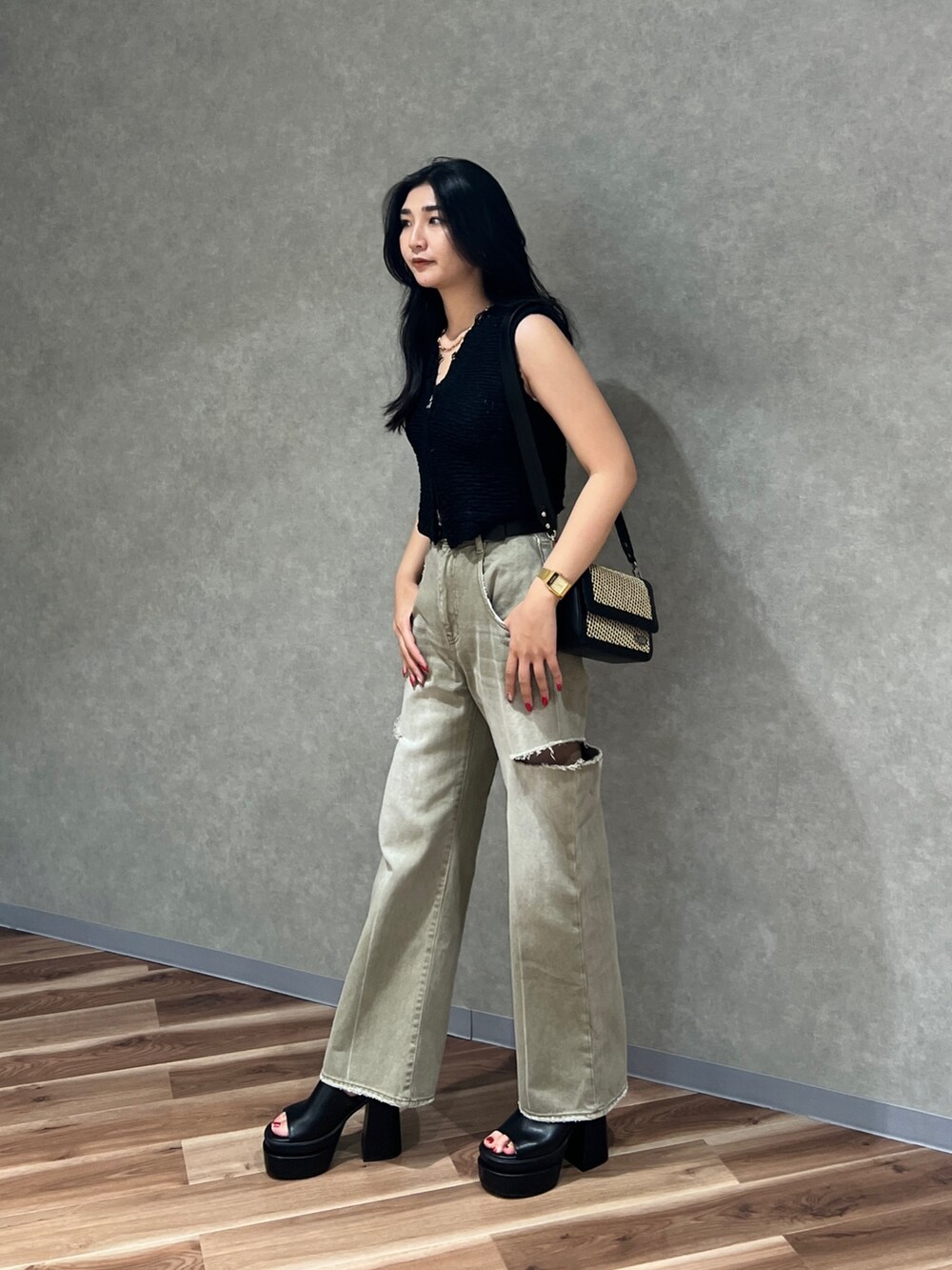 ブラック系のベスト、ホワイト系のニット/セーター、ベージュ系のデニムパンツを着用したレディースの夏コーディネートの2枚目の写真