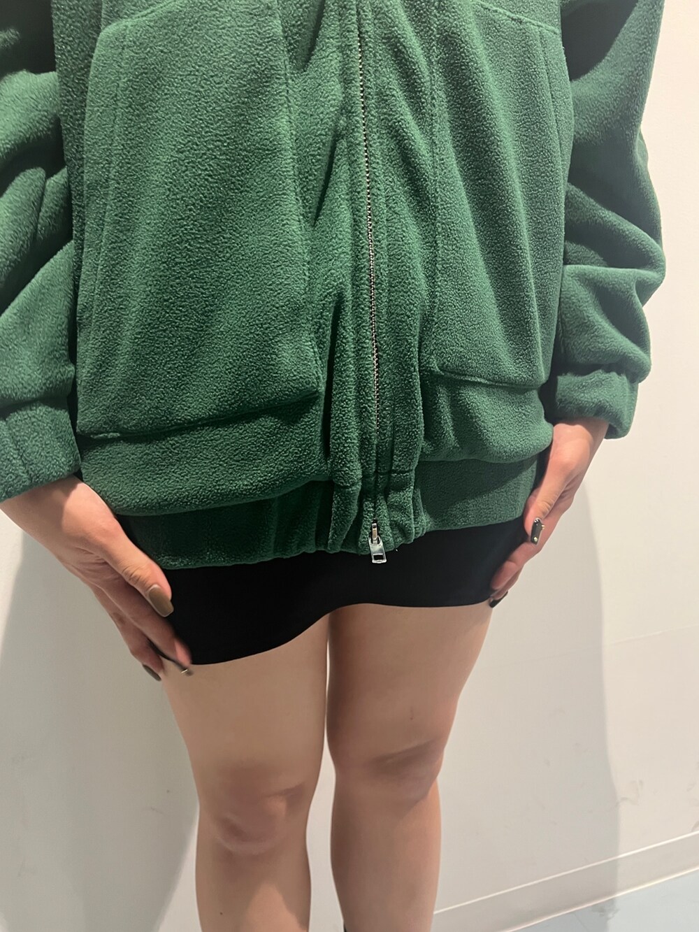 グリーン系のブルゾン、ブラック系のスカート、ブラック系のブーツを着用したレディースの秋コーディネートの5枚目の写真