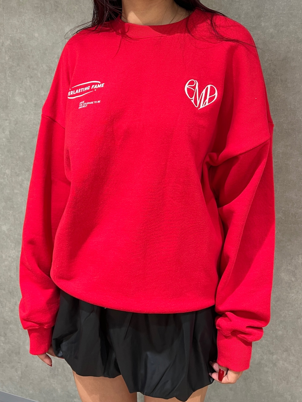 レッド系のスウェット、ブラック系のハンドバッグ、ブラック系のブーツを着用したレディースの秋コーディネートの4枚目の写真