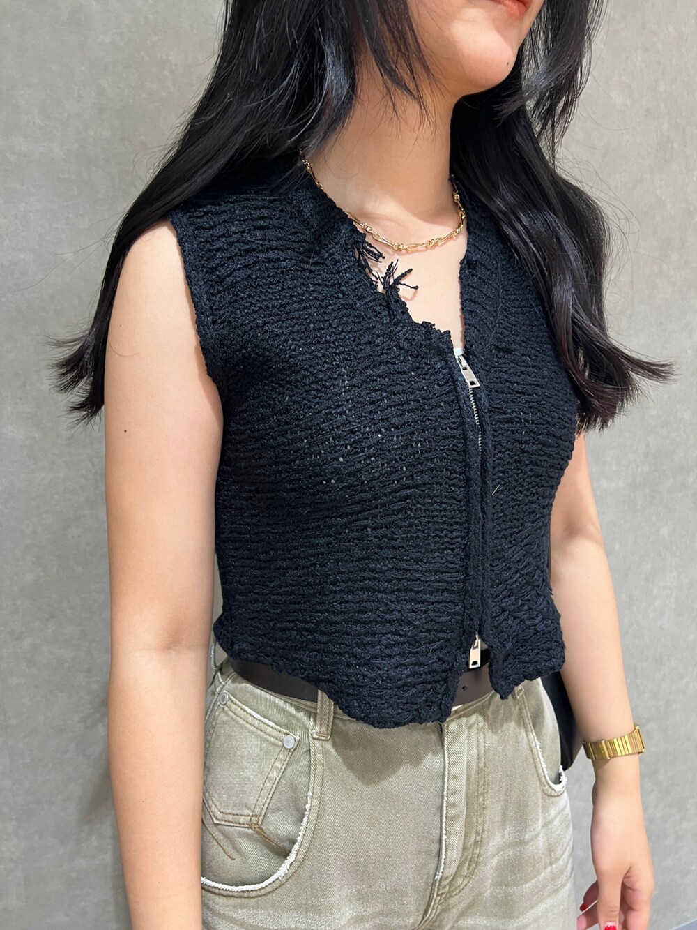 ブラック系のベスト、ホワイト系のニット/セーター、ベージュ系のデニムパンツを着用したレディースの夏コーディネートの4枚目の写真