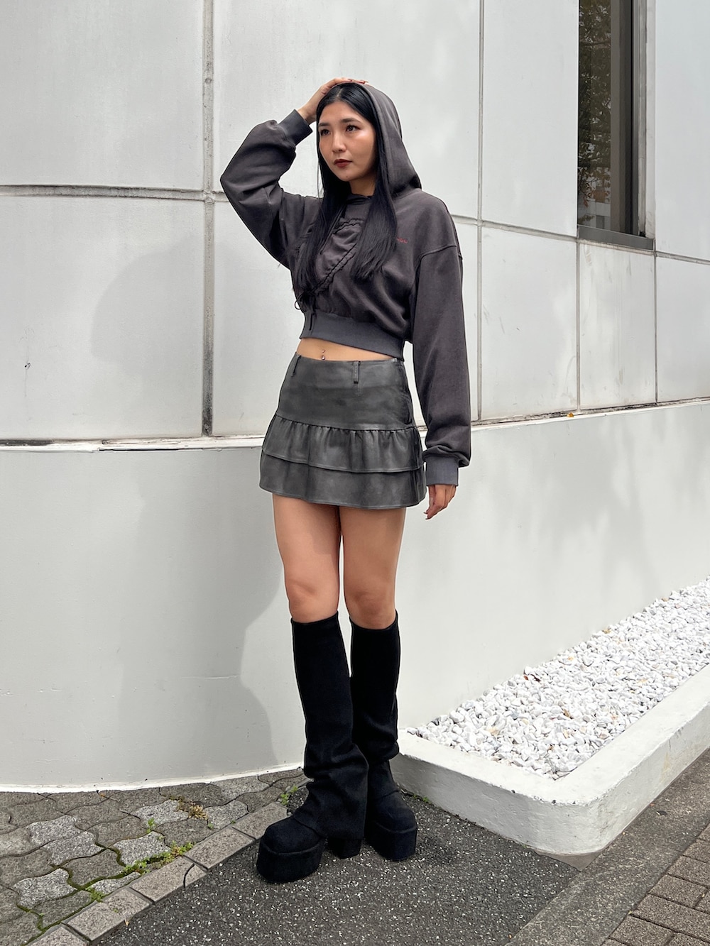 ブラック系のパーカー、グレー系のスカート、ブラック系のブーツを着用したレディースの秋コーディネートの2枚目の写真