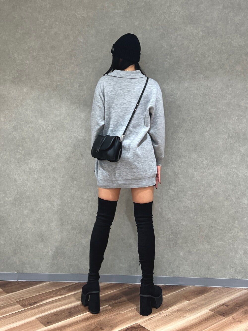グレー系のワンピース、ブラック系のスカート、ブラック系のブーツを着用したレディースの秋コーディネートの3枚目の写真