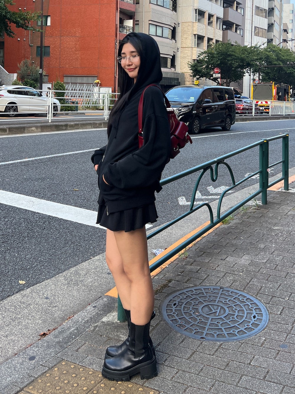 ブラック系のパーカー、ブラック系のスカート、レッド系のハンドバッグを着用したレディースの秋コーディネートの3枚目の写真