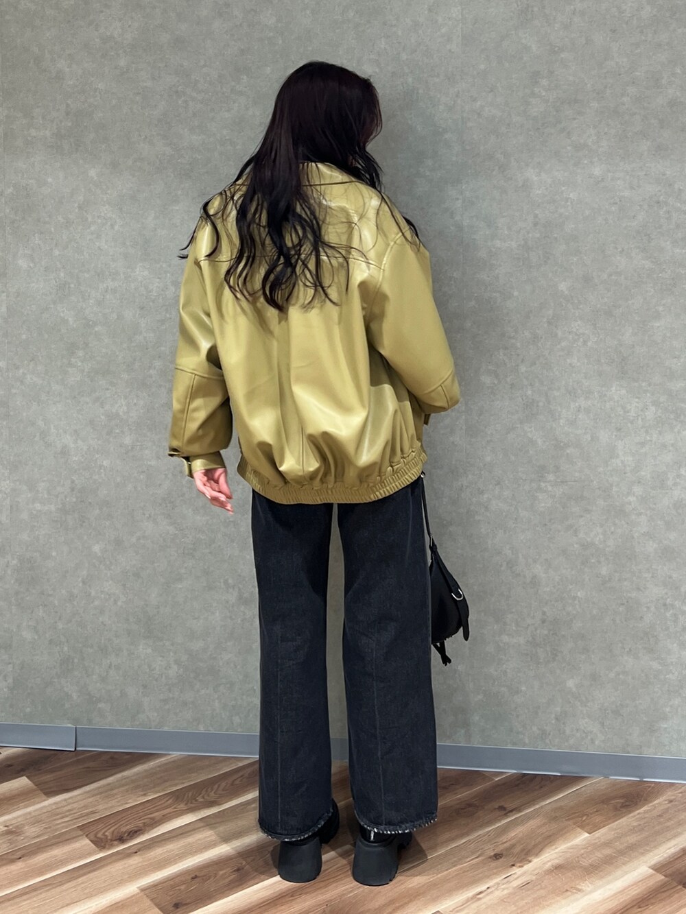 イエロー系のブルゾン、ブラック系のニット/セーター、ブラック系のデニムパンツを着用したレディースの冬コーディネートの3枚目の写真