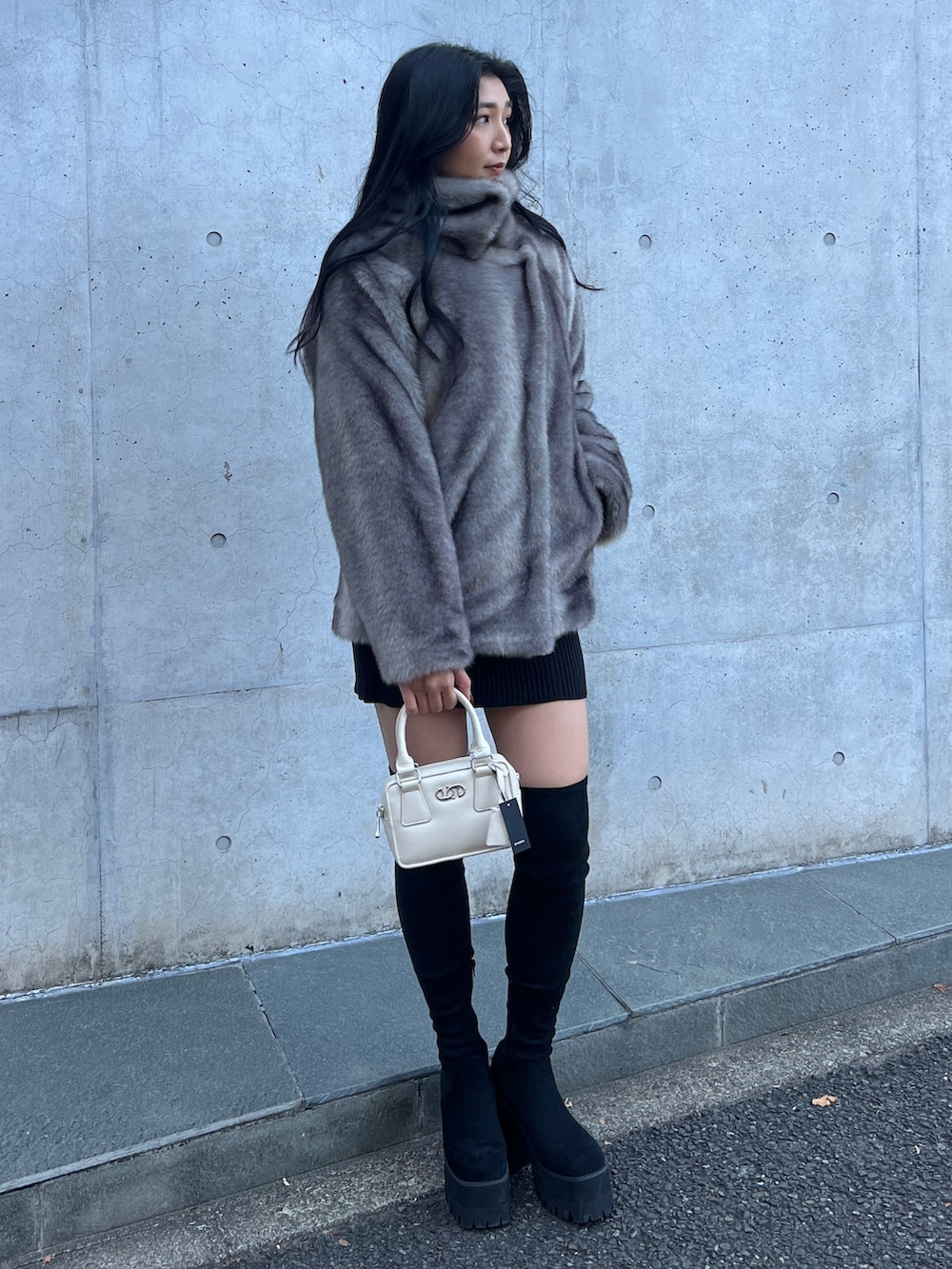 グレー系のその他アウター、ブラック系のワンピース、ブラック系のブーツを着用したレディースの冬コーディネートの2枚目の写真