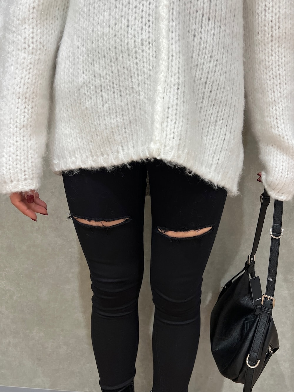 ホワイト系のニット/セーター、ブラック系のデニムパンツ、ブラック系のハンドバッグを着用したレディースの冬コーディネートの5枚目の写真