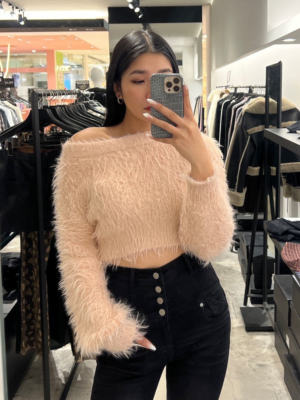 ピンク系のニット/セーター、ブラック系のデニムパンツ、ブラック系のブーツを着用したレディースの冬コーディネートの4枚目の写真