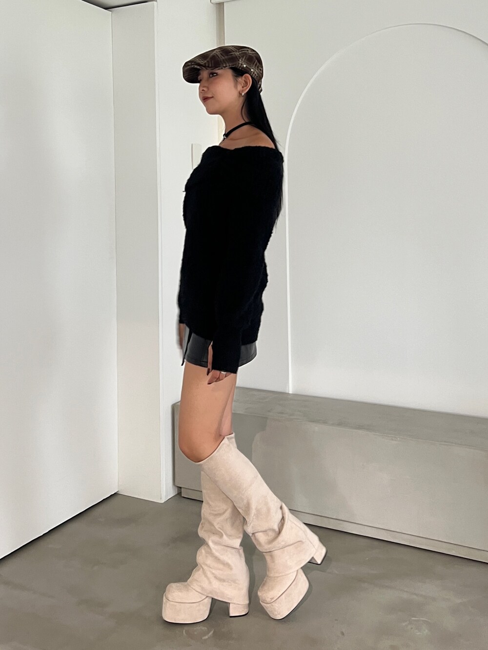 ブラック系のニット/セーター、ブラック系のスカート、ホワイト系のブーツを着用したレディースの秋コーディネートの2枚目の写真