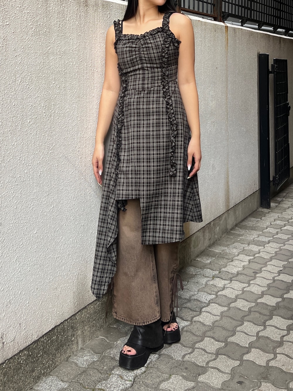 ブラック系のワンピース、ブラウン系のデニムパンツ、ブラック系のサンダルを着用したレディースの春コーディネートの2枚目の写真